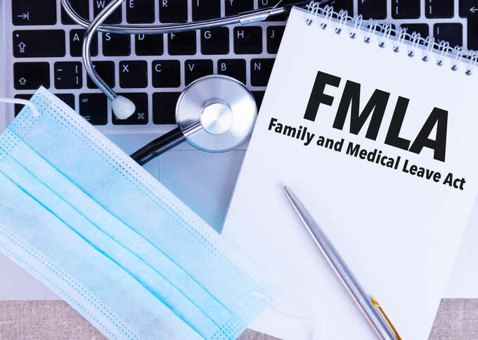 Laptop, surgical mask, stethoscope, and Family and Medical Leave Act (FMLA) labeled notebook