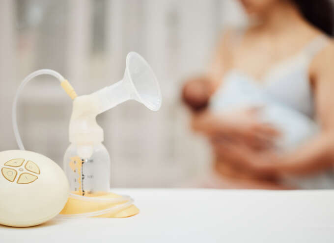 Breastfeeding pump with grainy image of mother breastfeeding an infant in the background